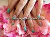 Acrylic nails with green gel polish and Swarovski crystals on ring finger